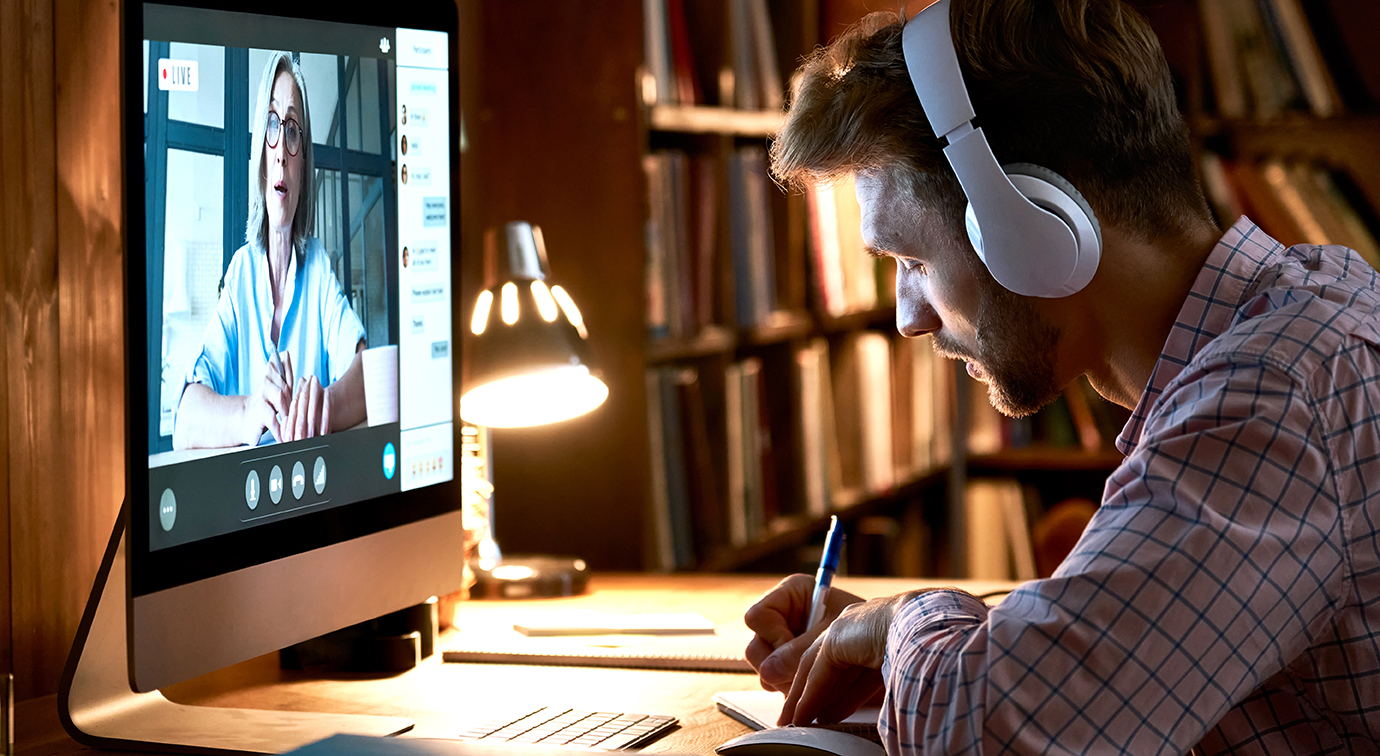Male student wearing headphones video conference calling watching webinar.